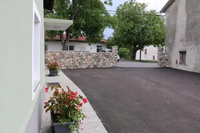 an empty parking lot with a stone wall and flowers at Apartmaji Lukovi in Obrov
