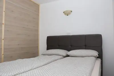 a bed with a black headboard and two pillows at Apartmaji Lukovi in Obrov