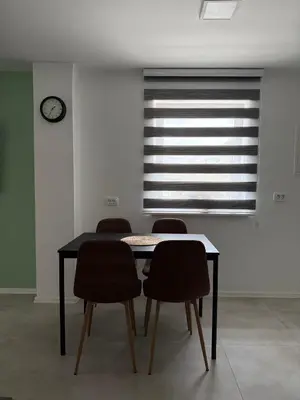 a dining room table with four chairs and a window at Natura Apartments in Kranj