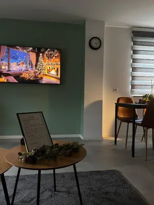 a living room with a table and a clock on the wall at Natura Apartments in Kranj