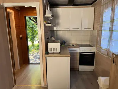 a small kitchen with white cabinets and a sink at Holzhaus in der Therme Čatež - familienfreundlich, Nähe WinterSommerRiviera in Brežice