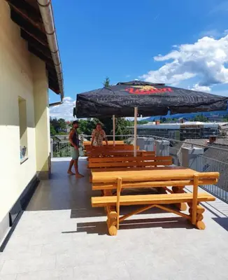 a group of benches and an umbrella on a building at Bled Hostel II in Bled