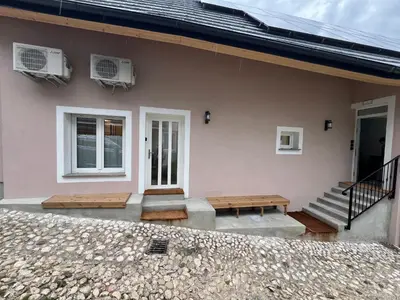 a house with two benches in front of it at Lazy Goose Charming Apartments Bovec in Bovec