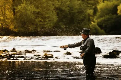 a man standing in a river holding a fishing rod at Pri Drevoredu in Prvačina