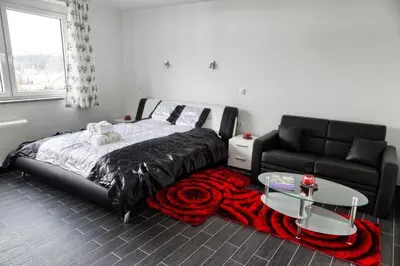 a bedroom with a bed and a black couch at Gril Ranca pod Pohorjem in Maribor