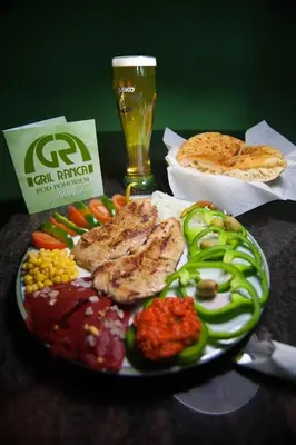 a plate of meat and vegetables with a glass of beer at Gril Ranca pod Pohorjem in Maribor