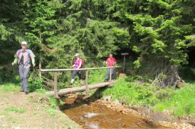 three people walking across a bridge over a creek at Gril Ranca pod Pohorjem in Maribor