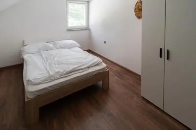 a bedroom with a bed with white sheets and a window at Hiša pod Veliko planino in Stahovica