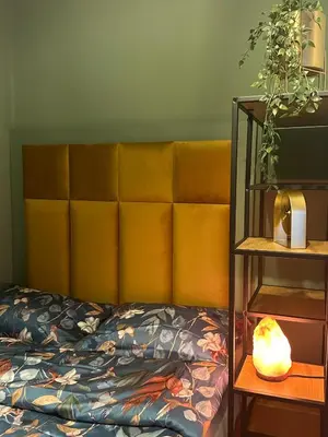 a bed with a yellow headboard next to a shelf at My Star Apartment in Maribor