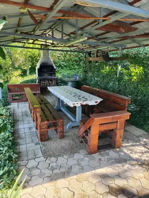 a picnic table and benches under a pergola at DATA Bivalni vikend in Gruškovec