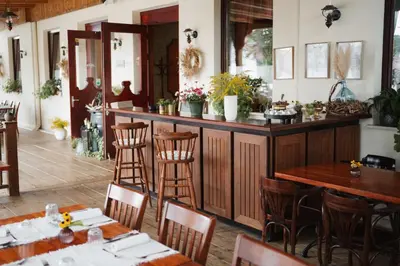 a restaurant with a bar with wooden chairs and tables at Stara šola Kaval in Novo Mesto