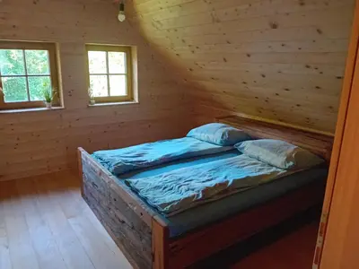 a bed in a log cabin with two windows at Hiša Šujica in Ljubljana