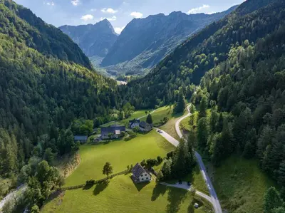 an aerial view of a house in a valley with mountains at Mala hiša in Solčava