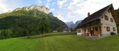 a house in a field with mountains in the background at Mala hiša in Solčava