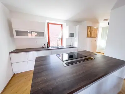 a kitchen with white cabinets and a black counter top at By the river Ljubljana apartment in Rove
