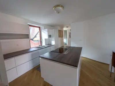 a kitchen with white cabinets and a black counter top at By the river Ljubljana apartment in Rove
