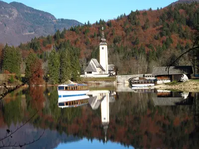 a church on a lake with a reflection in the water at Apartment Zalokar in Bohinj