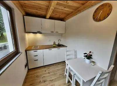 a kitchen with a table and chairs and a clock at Bungalov Čuk in Most na Soči