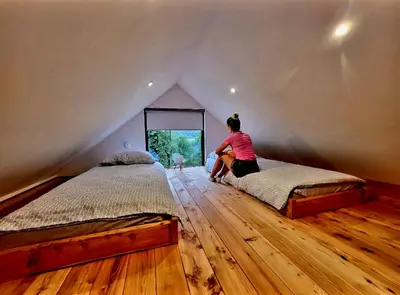 a woman sitting on a bed in a attic at Bungalov Čuk in Most na Soči