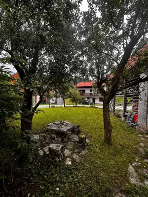 a stone bench in the middle of a yard with trees at Apartma Pr'Csrlu
