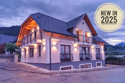 a building with lights on it with a new in text at Alpine House Mina - Rooms & Apartments in Bled