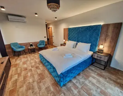 a bedroom with a large bed with a blue headboard at Alpine House Mina - Rooms & Apartments in Bled