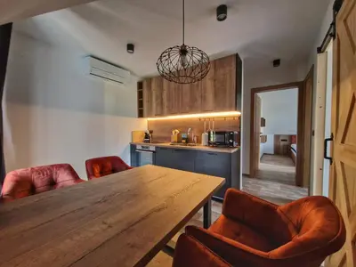 a kitchen with a wooden table and leather chairs at Alpine House Mina - Rooms & Apartments in Bled