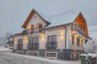 a house covered in snow with lights on it at Alpine House Mina - Rooms & Apartments in Bled