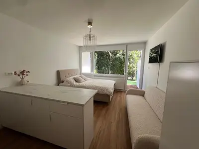 a white living room with a couch and a table at Designer City Oasis with Garden in Ljubljana