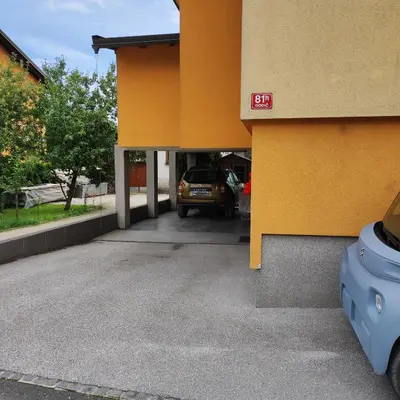 a yellow building with a car parked in a parking lot at Room under Velika planina in Stahovica