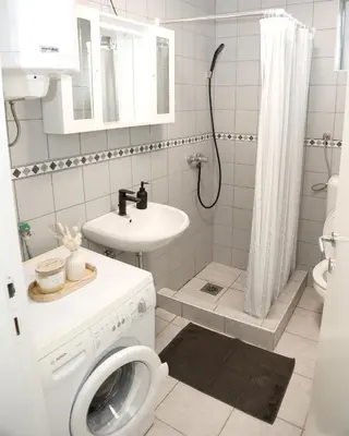 a white bathroom with a washing machine and a sink at Villa Volk in Ilirska Bistrica