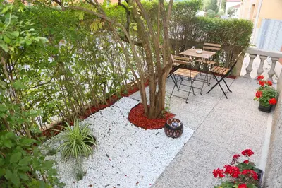 a patio with a table and a tree and flowers at Villa Volk in Ilirska Bistrica