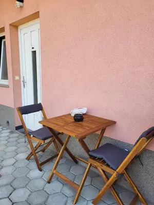 a wooden table and two chairs next to a pink wall at Studio AK in Žalec