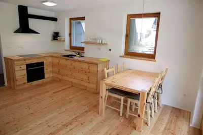 a kitchen with a wooden table and a table and chairs at Bled Forest Apartment in Bled