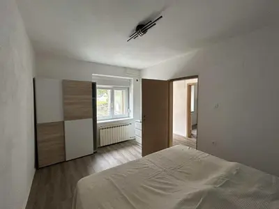a white bedroom with a bed and a window at Apartment Tonc in Kobarid