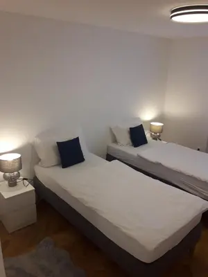 two beds in a small room with two lamps at Apartment Emona Ljubljana in Ljubljana