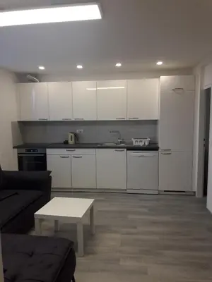 a kitchen with white cabinets and a table in a living room at Apartment Emona Ljubljana in Ljubljana