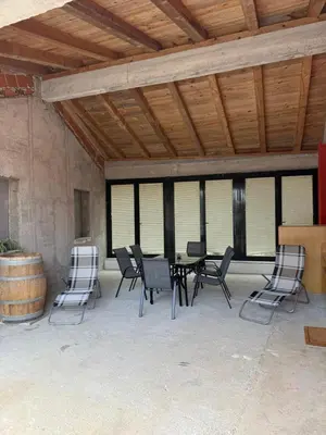 a patio with a table and chairs and a barrel at House Mohar in Lokev