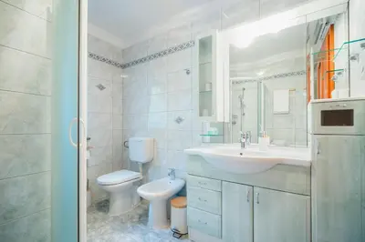 a white bathroom with a sink and a toilet at Spacious Apartment Senozece - with terrace & grill in Senožeče