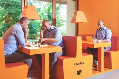 three men sitting at tables playing a chess game at Youth Hostel Proteus Postojna in Postojna