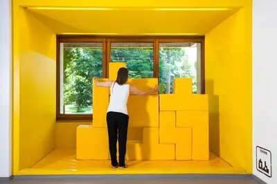 a woman looking out a window in a yellow room at Youth Hostel Proteus Postojna in Postojna