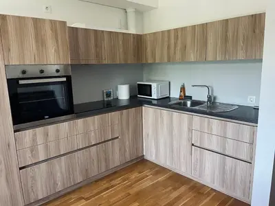 a kitchen with wooden cabinets and a microwave and a sink at Vitan Apartment in Bled