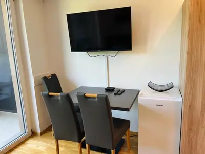 a room with a table with chairs and a television on the wall at Vitan Apartment in Bled