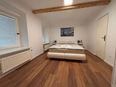 a bedroom with a bed in a room with wooden floors at The Green City Apartment in Ljubljana