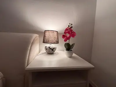 a table with a lamp and a flower on it at The Green City Apartment in Ljubljana