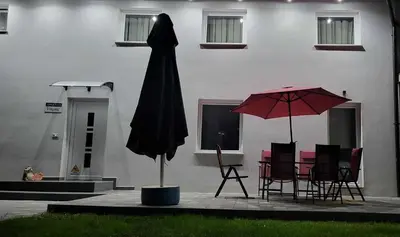 a black umbrella and chairs and a table with a red umbrella at Apartma Viković