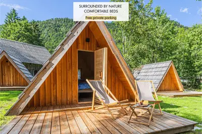 a large wooden house with two chairs on a deck at Glamping Radovna pr' Klemenak in Zgornje Gorje