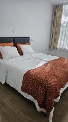 a large bed with an orange and white blanket on it at Memento Ljubljana Apartments with Private Bathrooms & Shared Kitchen in Ljubljana