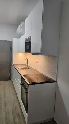 a kitchen with white cabinets and a sink and a refrigerator at Memento Ljubljana Apartments with Private Bathrooms & Shared Kitchen in Ljubljana