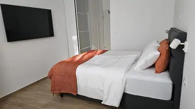 a bedroom with a bed and a tv on a wall at Memento Ljubljana Apartments with Private Bathrooms & Shared Kitchen in Ljubljana